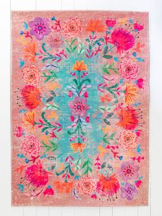 a pink rug with colorful flowers on the front and back, against a white wall