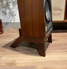 a wooden speaker stands on top of a hard wood floor