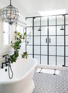 a white bathroom with black and white tile on the floor, shower head, and bathtub