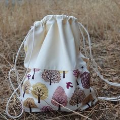 a drawstring bag sitting in the middle of some dry grass with trees on it