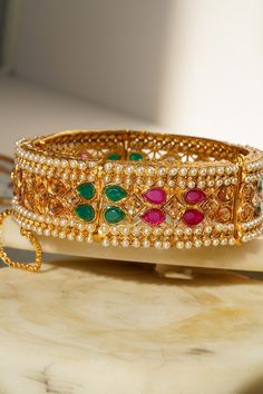 Introducing the Amika Bangle Set (Set of 2), a stunning addition to any jewelry collection. These gold-plated bangles feature intricate designs adorned with pearls and vibrant multicolor stones, including green and ruby accents. The detailed floral and petal patterns exude elegance and sophistication, making these bangles & bracelets set perfect for desi weddings and special occasions. The Amika Bangle Set showcases the timeless beauty of Navratan craftsmanship. The bangles are designed with an Gold Plated Bangles, Bangle Bracelet Set, Bracelets Set, Bangles Bracelets, Desi Wedding, Bangle Set, Bracelet Set, Timeless Beauty, Faux Pearl