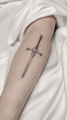 a black and white photo of a person with a knife tattoo on their arm