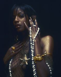 a woman with gold jewelry and pearls on her hands