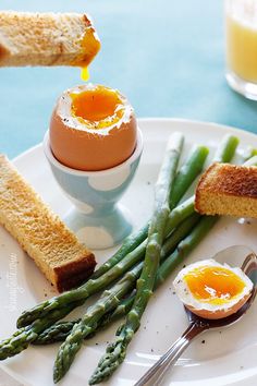 a plate with eggs, asparagus and toast on it next to a glass of orange juice