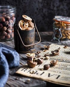 an image of nuts in a jar on top of a wooden table next to a newspaper