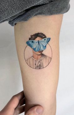 a woman's arm with a blue butterfly on her head and the image of a man behind it