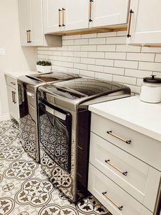 a stove top oven sitting inside of a kitchen next to white cupboards and drawers