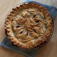 a pie sitting on top of a wooden table next to a blue napkin and fork