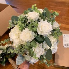 a bouquet of white flowers sitting on top of a wooden table next to a cardboard box