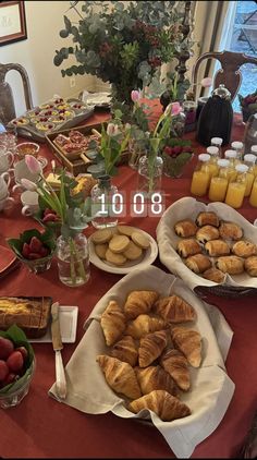 an assortment of pastries and fruit on a table with flowers in vases next to them