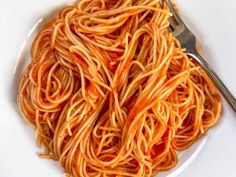 a white plate topped with spaghetti next to a fork