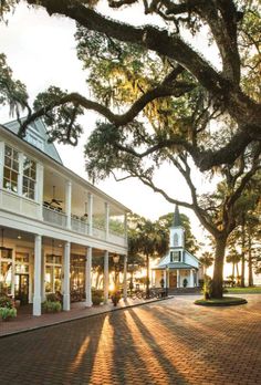 the sun shines through the trees in front of a white building with columns and pillars