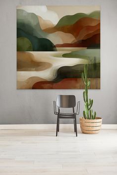 an abstract painting hangs on the wall above a chair in a room with a potted cactus