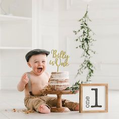 a baby boy sitting in front of a cake