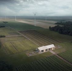 an aerial view of a farm with windmills in the distance and fields around it