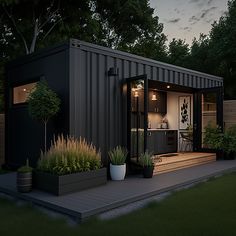 a small house made out of shipping containers in the evening with plants and potted plants