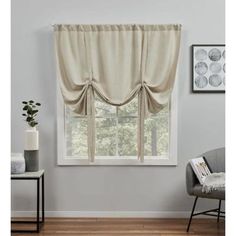 a living room with a chair and window in front of the window, it has a curtain