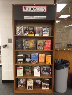 a bookshelf filled with lots of books next to a trash can in a library