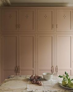 a table topped with plates and bowls filled with food next to cupboards covered in pink paint