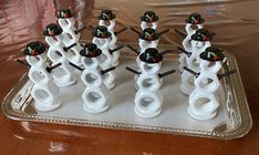 there are many snowmen made out of plastic pipes on the tray, with black and white knobs