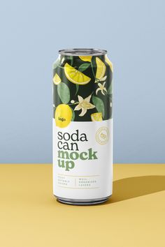 a can of soda with lemons and green leaves on the top, sitting on a yellow surface