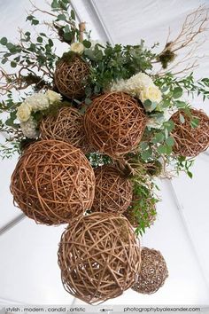 a bunch of wicker balls with flowers in them sitting on a white table cloth