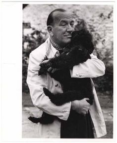 black and white photograph of a man holding a cat in his arms while wearing a coat