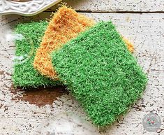 two pieces of fake grass sitting on top of a wooden table next to a plate