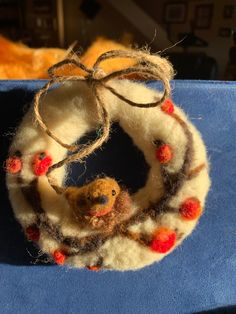 a close up of a stuffed animal in a wreath on top of a blue surface