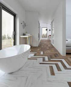 an image of a white bathroom with wood flooring and large tub in the middle