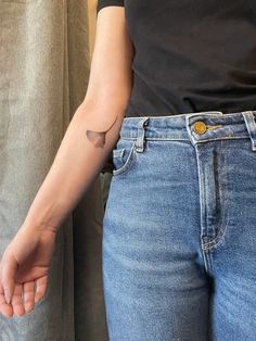 a person with a small tattoo on their arm standing next to another person wearing jeans