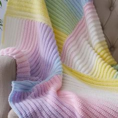 a multicolored blanket sitting on top of a couch next to a white chair