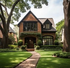 a brick house surrounded by lush green grass and trees in front of it is a pathway leading to the front door