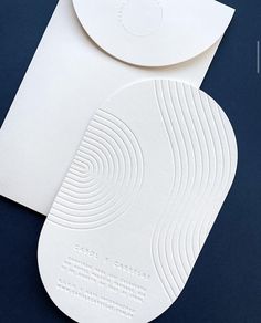 two white business cards on top of each other next to an envelope with a circular design