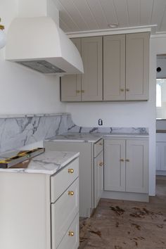 an empty kitchen with marble counter tops and white cabinets in the middle of the room