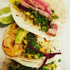 three tacos with shrimp, broccoli and other toppings on a white plate