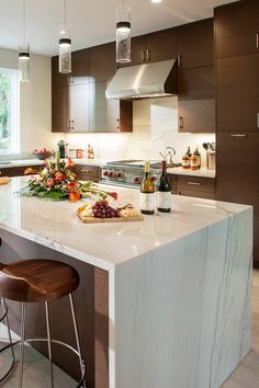 a kitchen with an island and bar stools in front of the countertop area