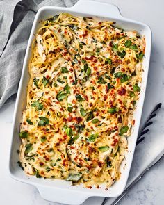 a casserole dish filled with pasta, cheese and spinach sprinkled with seasonings