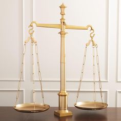 a golden balance scale sitting on top of a wooden table