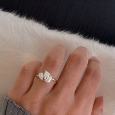 a woman's hand with a diamond ring on top of her finger and white fur