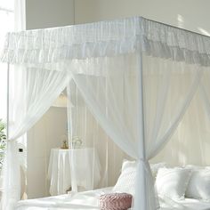 a white canopy bed sitting in a bedroom next to a window