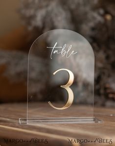 a glass table number with the number three in gold on it's front and back sides