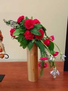 a vase filled with flowers sitting on top of a wooden table next to a figurine