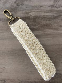 a crocheted keychain is shown on a wooden surface with a metal hook