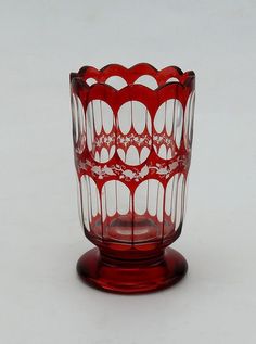 a red glass vase sitting on top of a white table