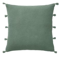 a green pillow with pom poms on the front and back of it, against a white background