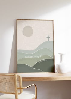 a white vase sitting on top of a wooden table next to a framed cross poster