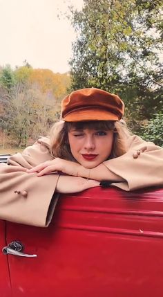 a woman leaning on top of a red car