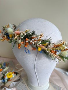 a white headpiece with flowers and leaves on it's side, sitting on top of a mannequin