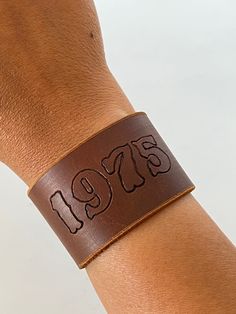 "1.5\" cuff with your year of birth stamped on each piece. Post closure with 4 holes for sizing options.  Available in Tan (Cognac), Black.   Ready to ship in 1 business day via USPS First Class Mail.  Please message me with any questions! Thanks please note that due to the natural occurring variations of the leather, and various colorizations on computer screens or phone screens, colors can vary slightly from pictures listed." Western Bracelets, Leather Cuff Bracelet, Phone Screens, Leather Art, Leather Cuffs Bracelet, Bracelet Cuff, Leather Cuffs, Brown Color, Cuff Bracelet